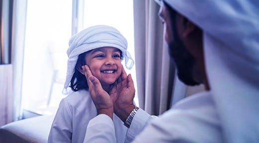 رجل يحمل وجه طفله، مما يعكس الأمان والاستقرار الذي يمكن تحقيقه من خلال إعادة تمويل الرهن العقاري مع بنك أبوظبي الأول الإسلامي.