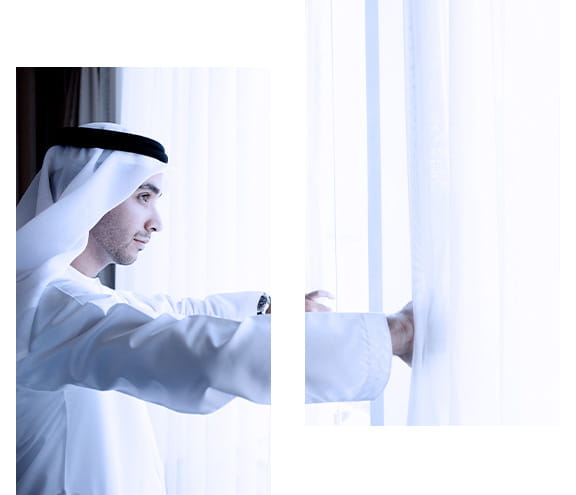رجل يستمتع بالمنظر من نافذة منزل أحلامه بفضل التمويل السكني الإسلامي من بنك أبوظبي الأول الإسلامي