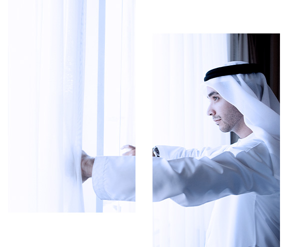 Man looking out the window of his dream home, financed by FAB Islamic Home Finance.