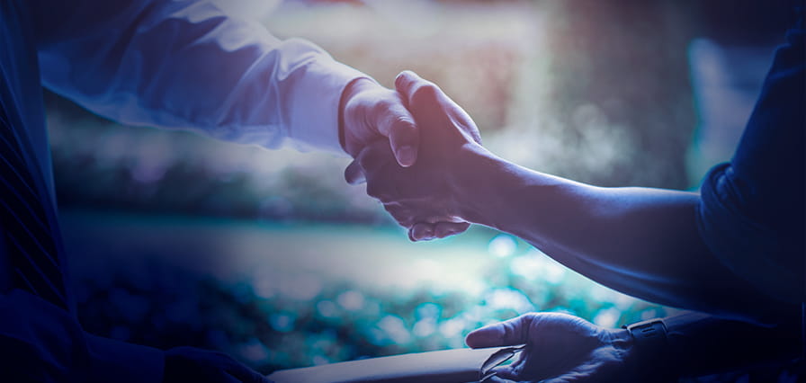 موظف البنك يصافح عميلًا بعد إتمام اتفاقية قرض بنجاح بمساعدة حاسبة القروض من بنك أبوظبي الأول.