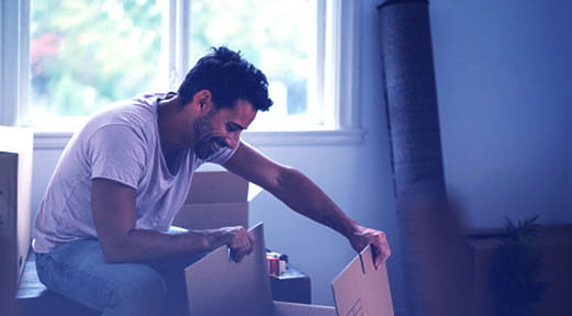 رجل يفتح صندوقاً في منزله الجديد بفضل تمويل أول منزل من بنك أبوظبي الأول.