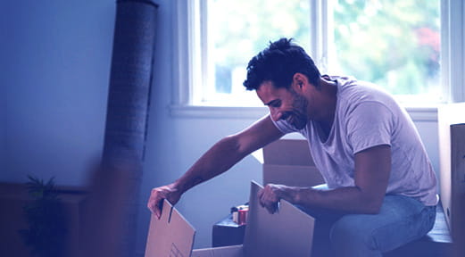 Man opening a box in his new home with FAB's First-Time Home Buyer Mortgage.